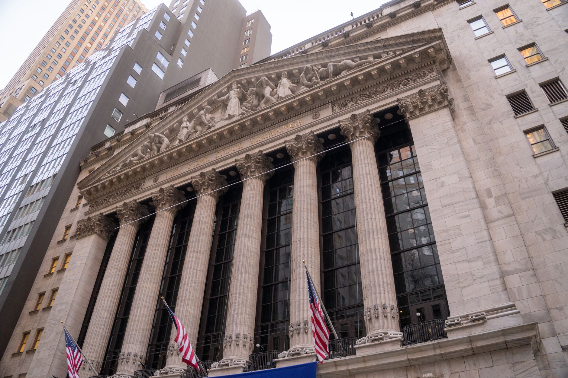 Close-up view of the iconic New York Stock Exchange building with American flags, located in Wall Street, NYC.