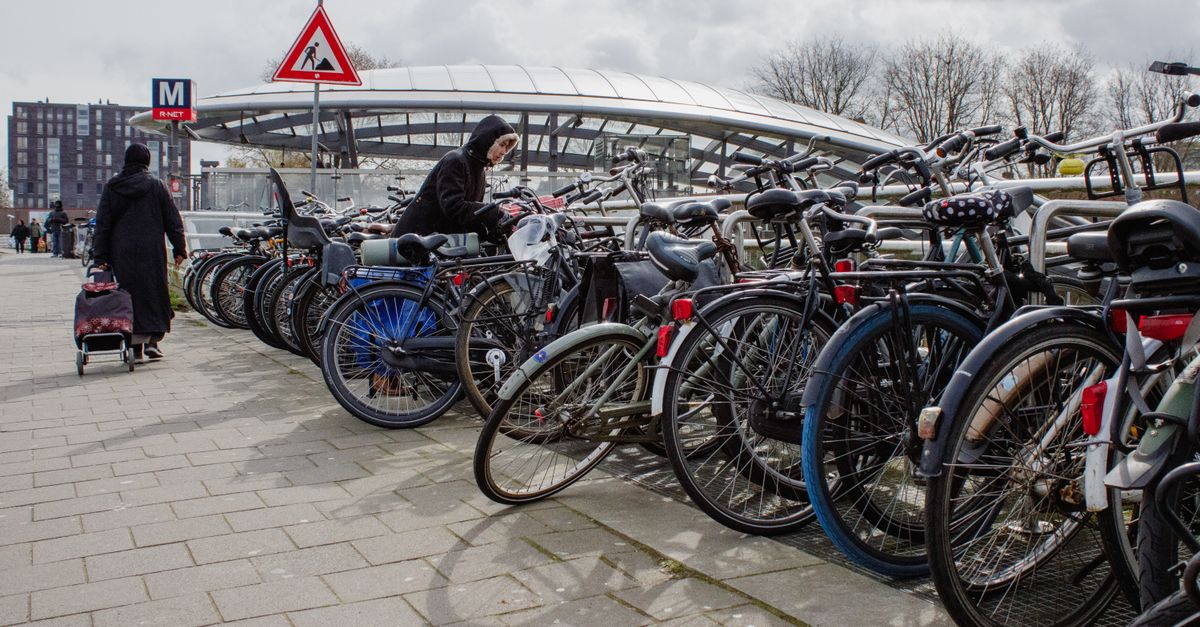 Bicycles parked near a metro station entrance on a cloudy day, urban commuting scene.