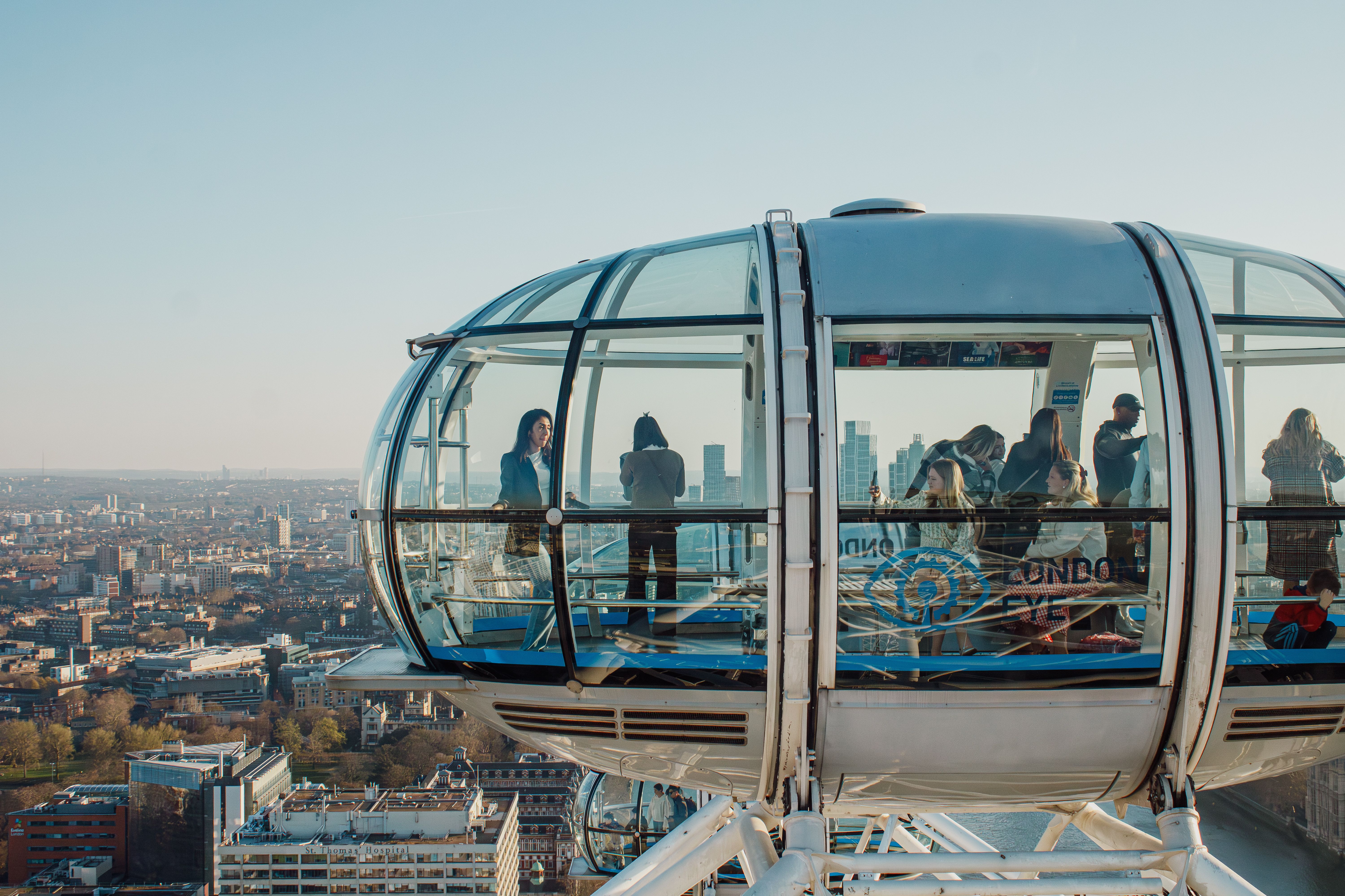 Passengers inside a glass London Eye capsule looking out over the London skyline during a rotation