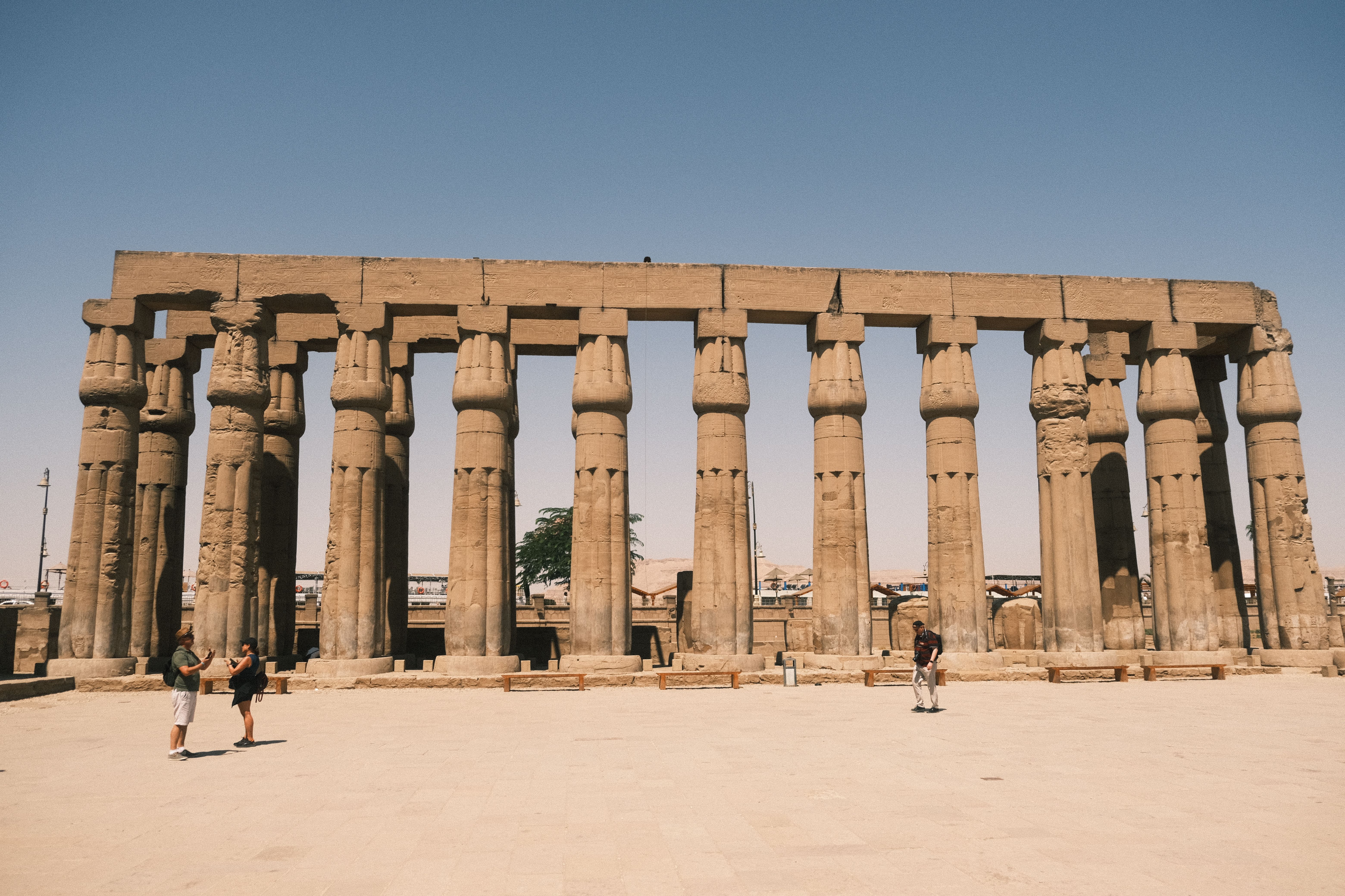 Quiet colonnade at Medinet Habu temple with few tourists in warm afternoon light