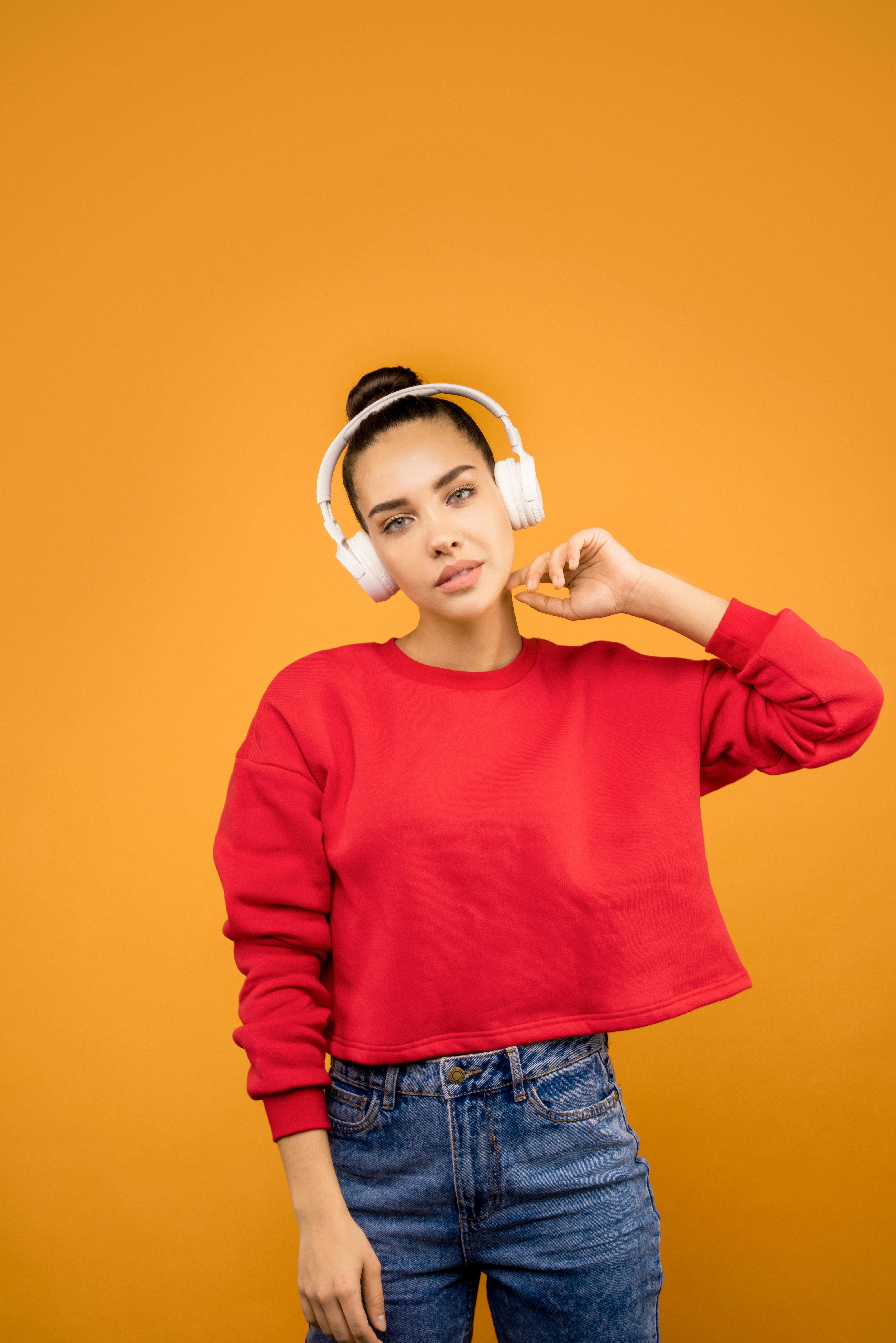 girl in red crop top wearing white headphones