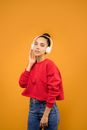 Woman in Red Sweatshirt and Blue Jeans Wearing White Headphones