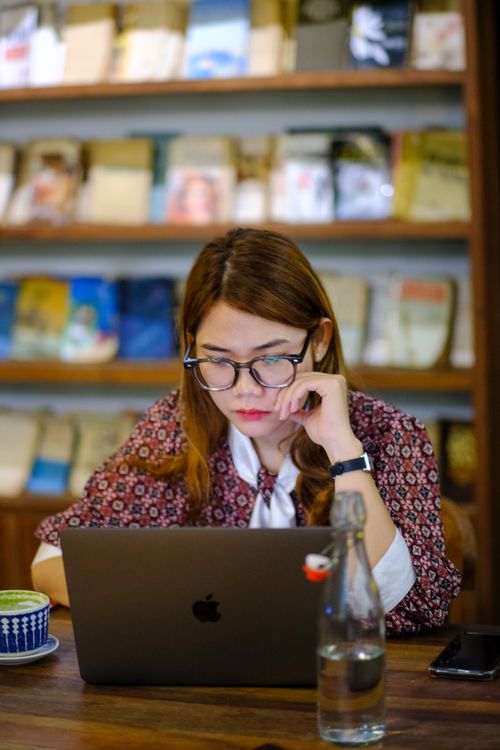 Free Young woman working focused on a laptop in a cozy cafe setting in Hue, Vietnam. Stock Photo
