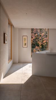 A serene minimalist interior showcasing autumn foliage through a large window.