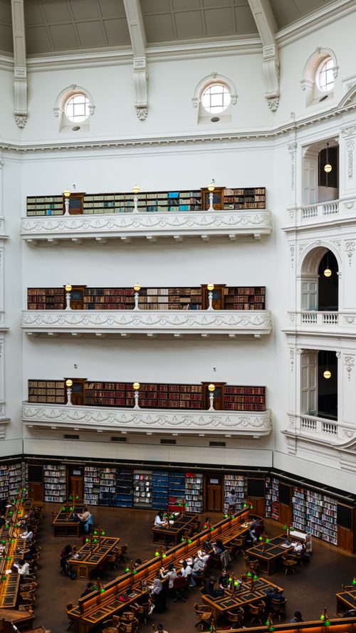 Free Elegant library interior showcasing multiple ornate balconies with shelves stacked with books. Stock Photo