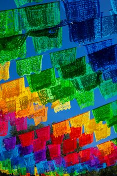 Colorful papel picado decorations under vibrant blue skies in Tlaxcala, Mexico.