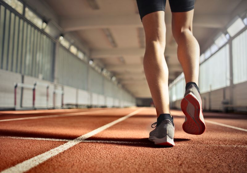A runner's legs mid-stride on an indoor running track