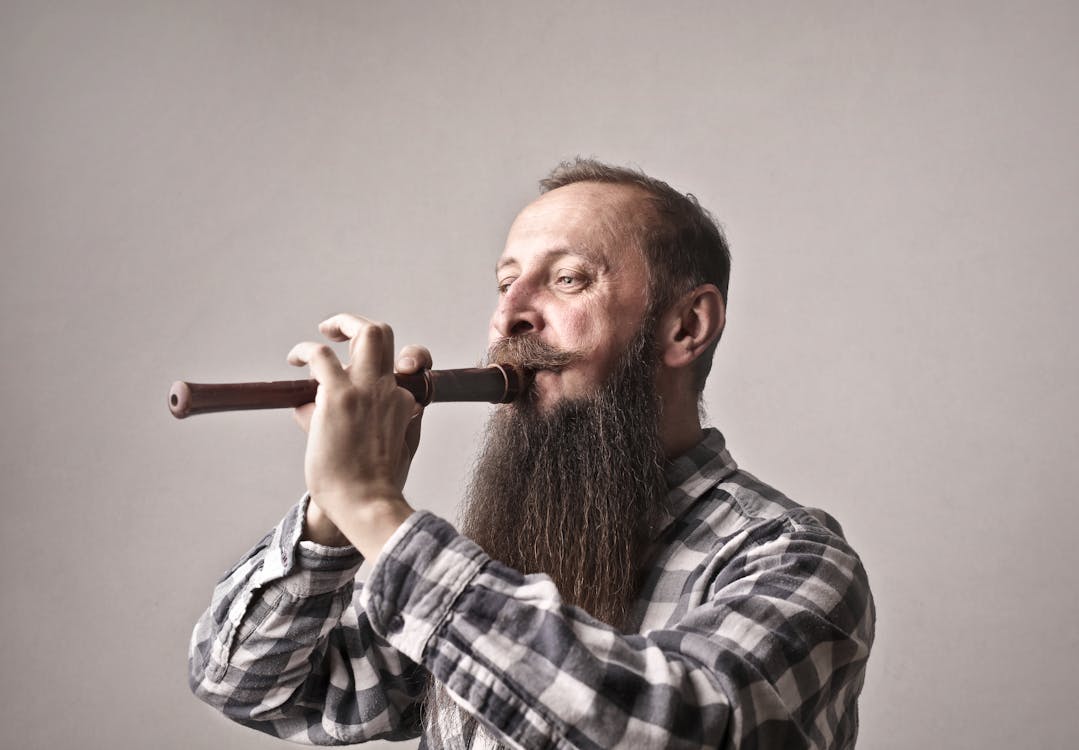 Man in Black and White Plaid Dress Shirt Playing Flute
