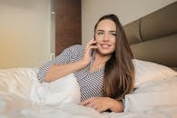 一个长发女人躺在床上，开心地打着电话