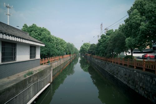 Free A peaceful canal lined with lush green trees and traditional architecture. Stock Photo