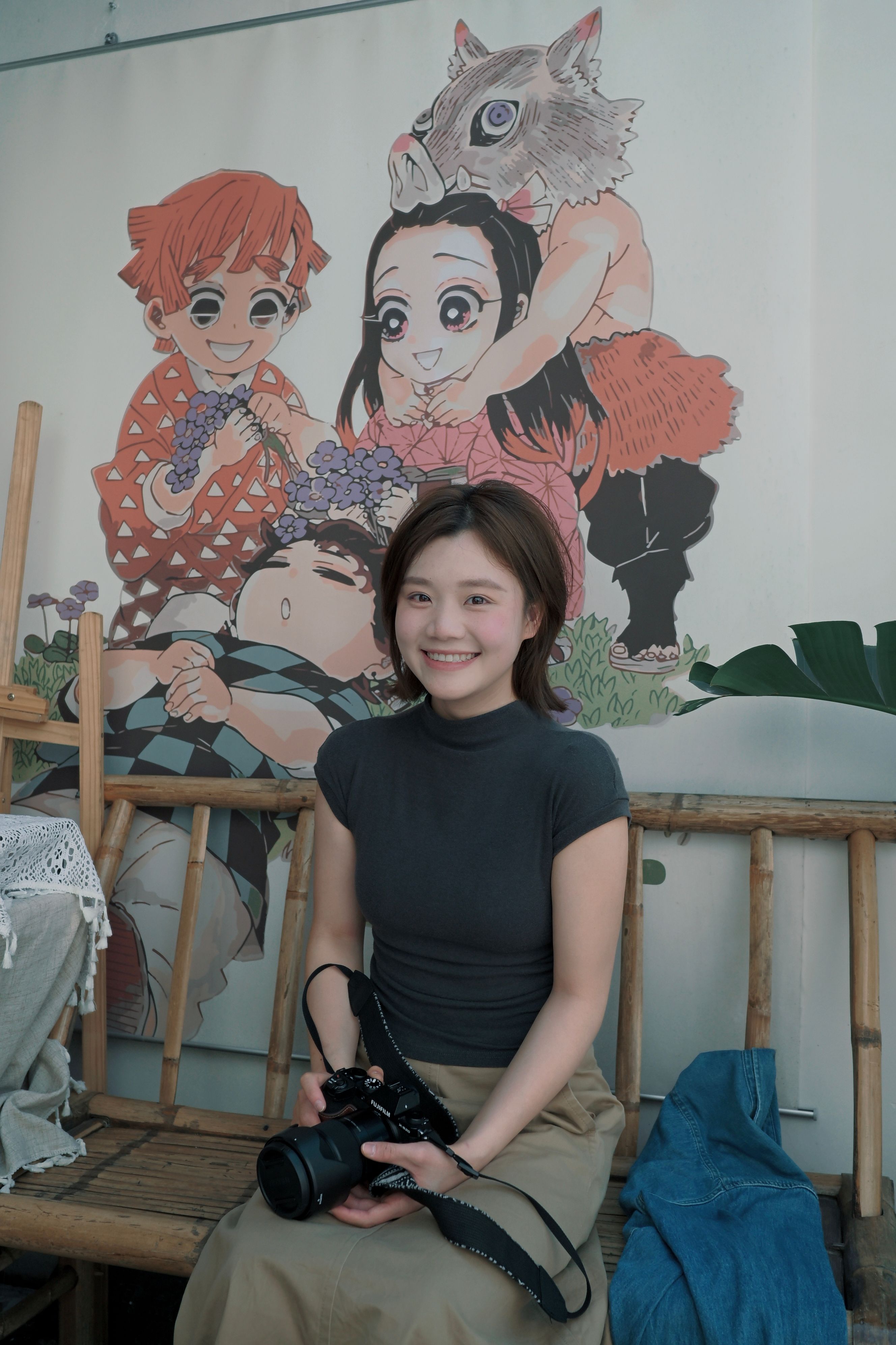 Young female photographer seated in studio with anime art backdrop.