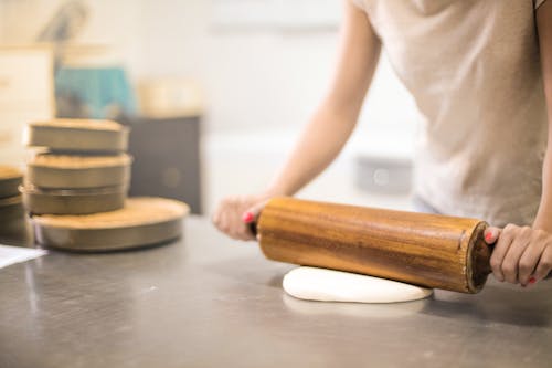 Free Person in White T-shirt Rolling a Pin in Dough Stock Photo