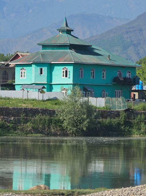 Free Charming turquoise house reflecting in a tranquil lake amidst mountains. Stock Photo