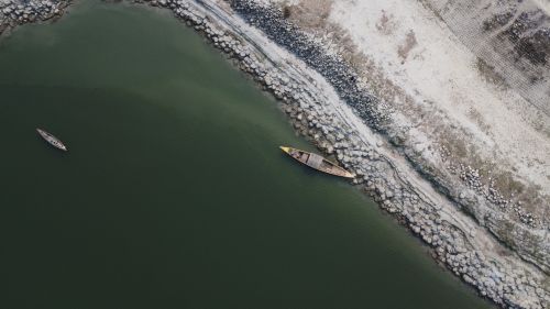 Free Aerial view of two boats by a rocky riverbank, capturing tranquil waters and rugged shorelines. Stock Photo