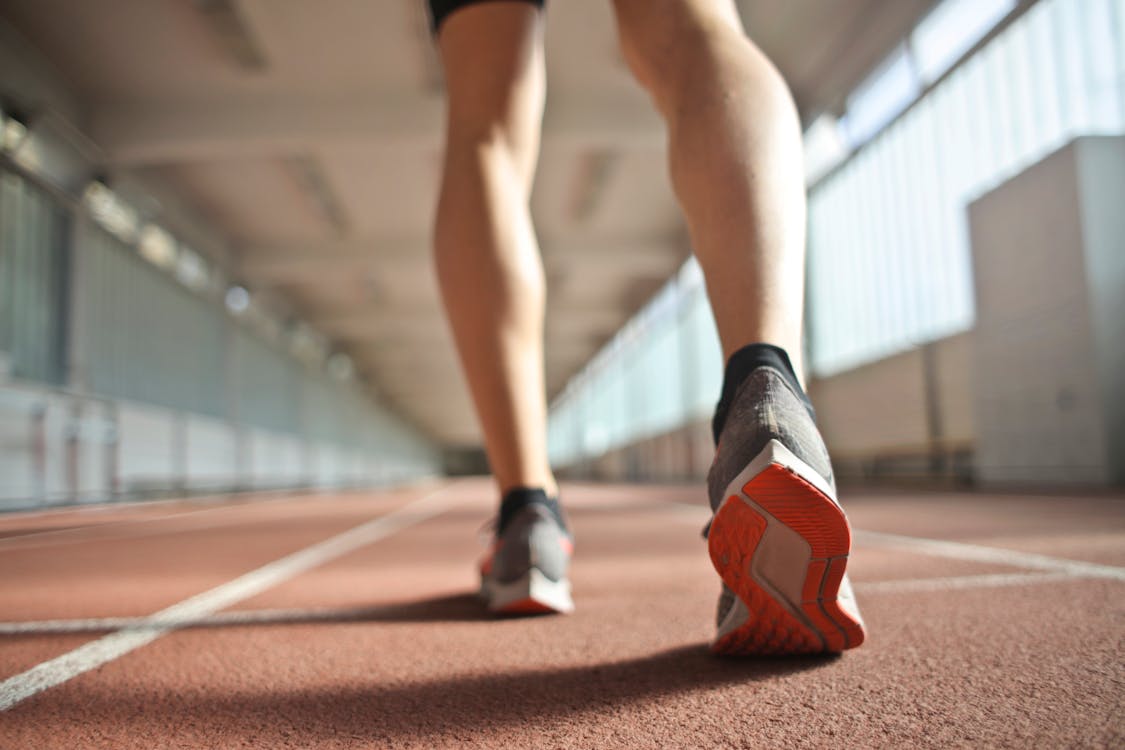 Fit runner standing on racetrack in athletics arena