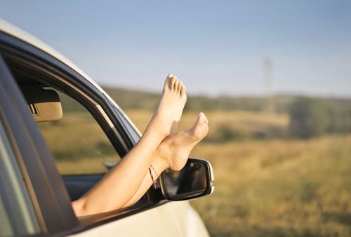 Free Crop carefree woman with legs sticking out of car window Stock Photo