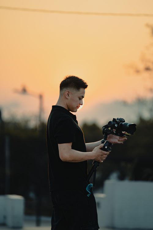 Free A photographer adjusts his camera during a picturesque Benidorm sunset, capturing the serene surroundings. Stock Photo