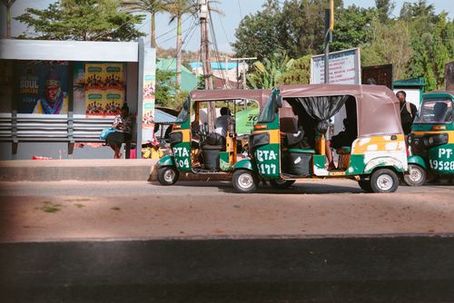 Free Colorful rickshaws and a bus stop in Jos, Plateau, Nigeria capture city life. Stock Photo