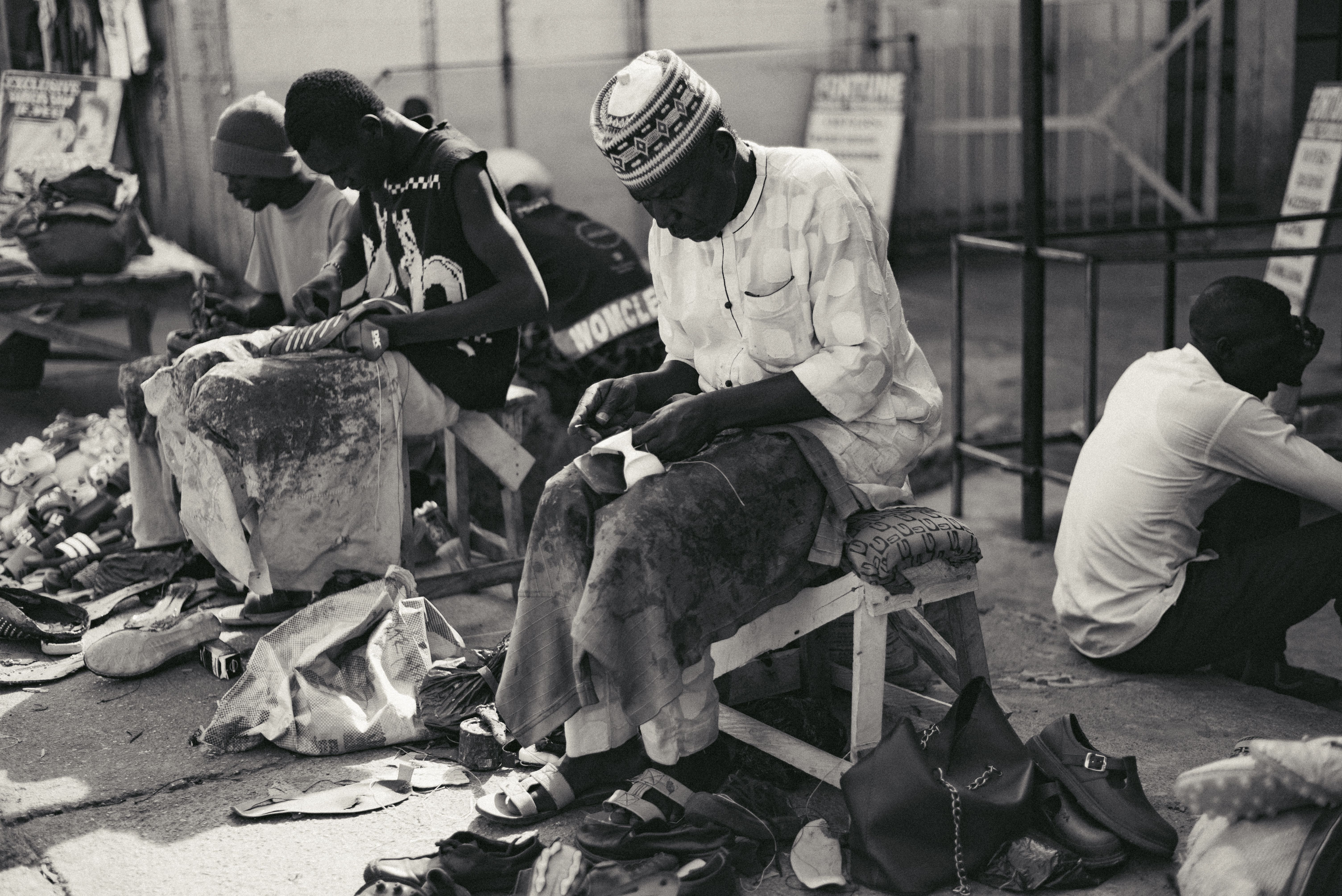 Artisans at work repairing shoes in an outdoor market in Jos, Nigeria.