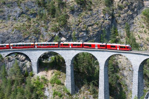 Free Stunning view of a red train crossing the iconic Landwasser Viaduct in the Swiss Alps. Stock Photo
