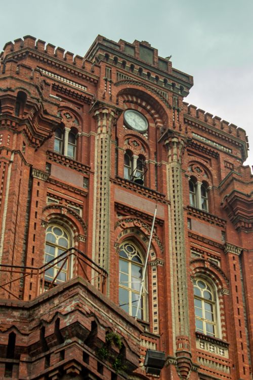 Free Detailed view of a historic red brick building facade with ornate architectural features. Stock Photo