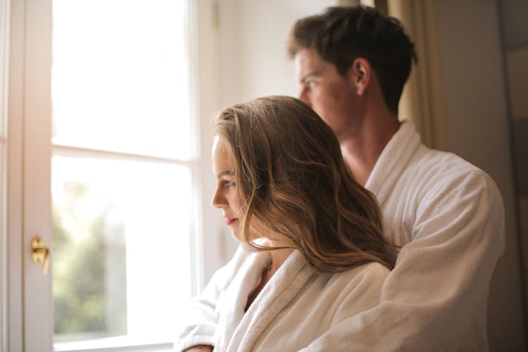 Gentle Couple Hugging Near Window At Home