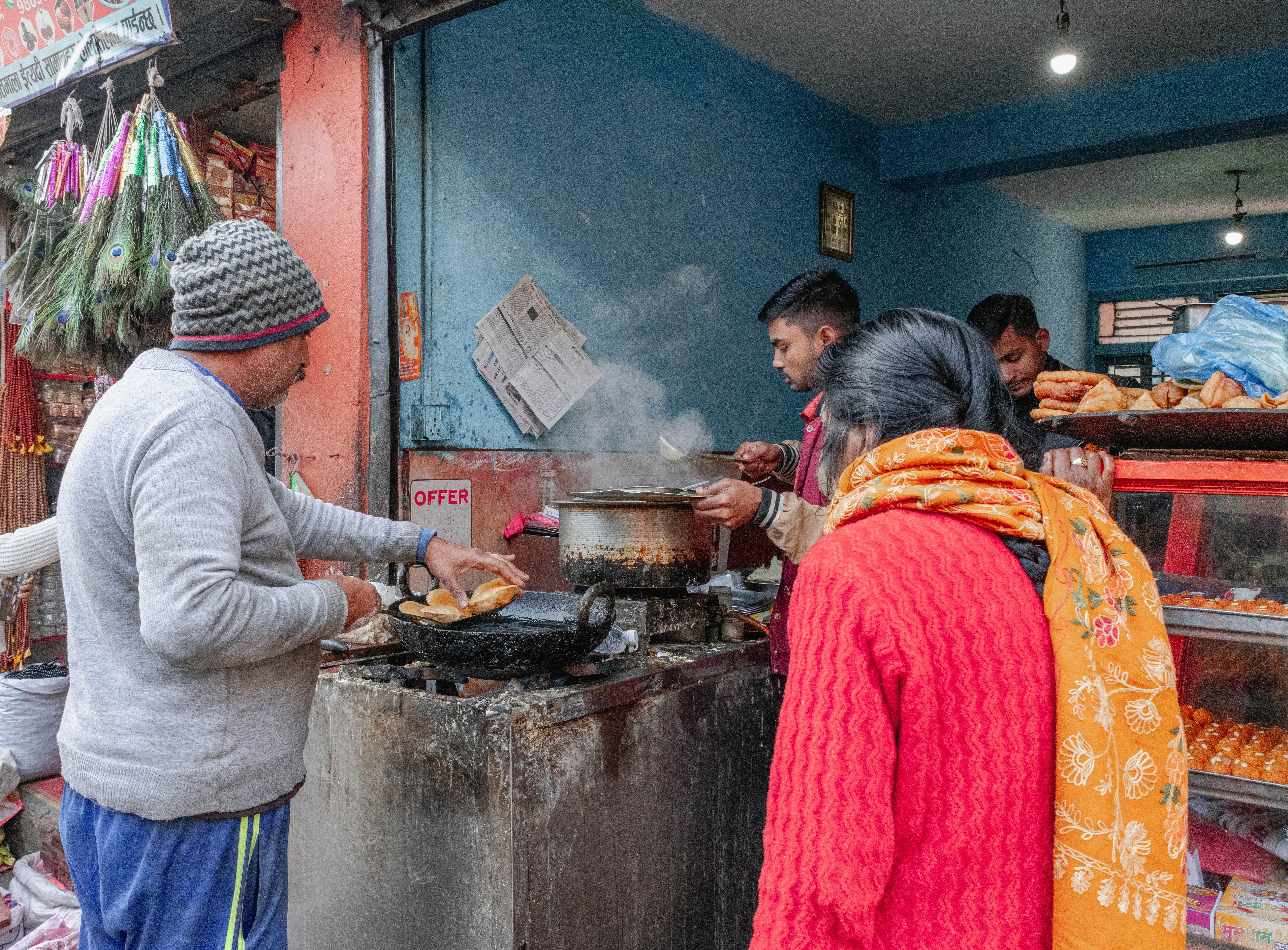 People cooking and serving food at a bustling street food stall in Kathmandu, Nepal.