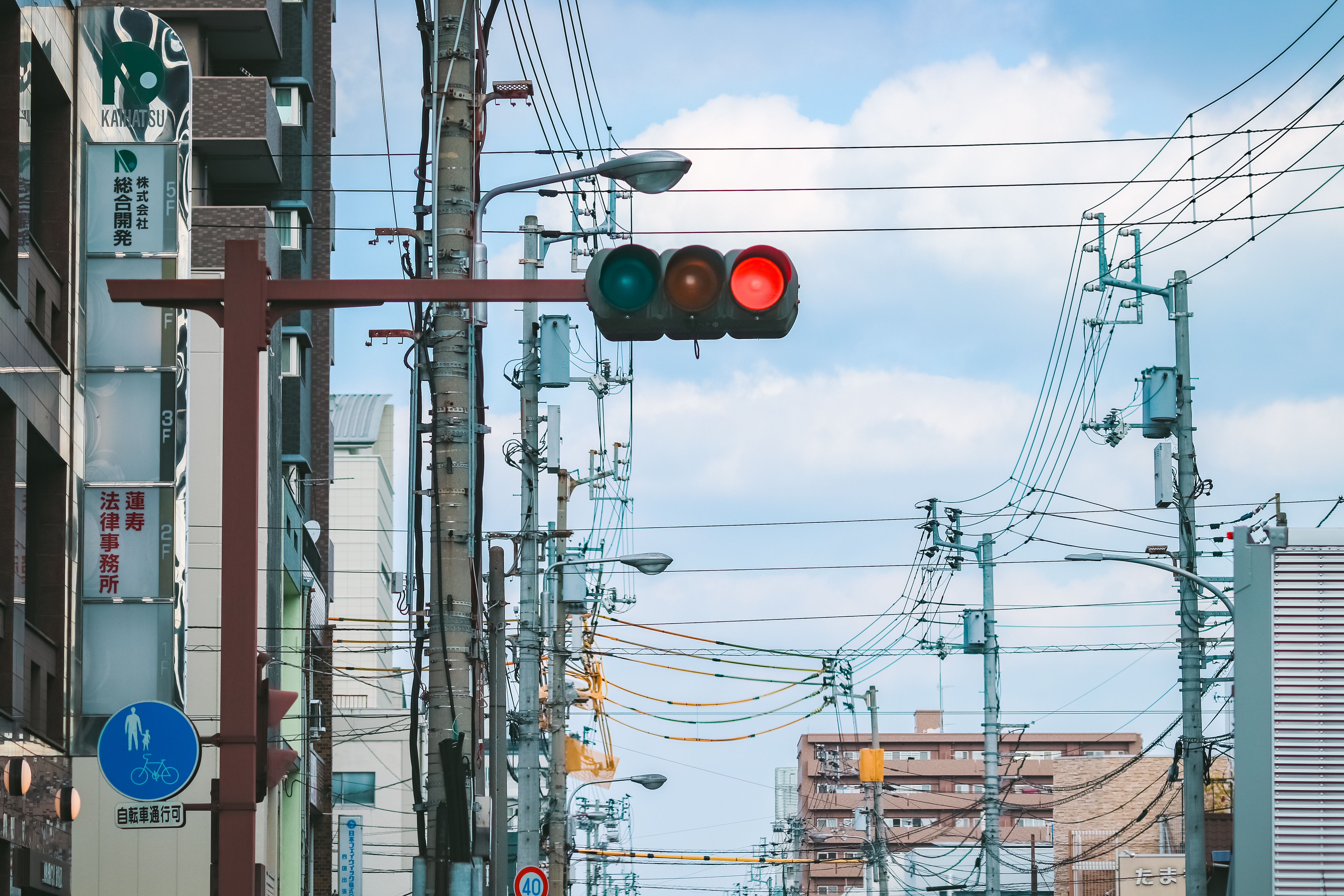 City street in Kagawa, Japan, featuring traffic lights and overhead wires under a blue sky.