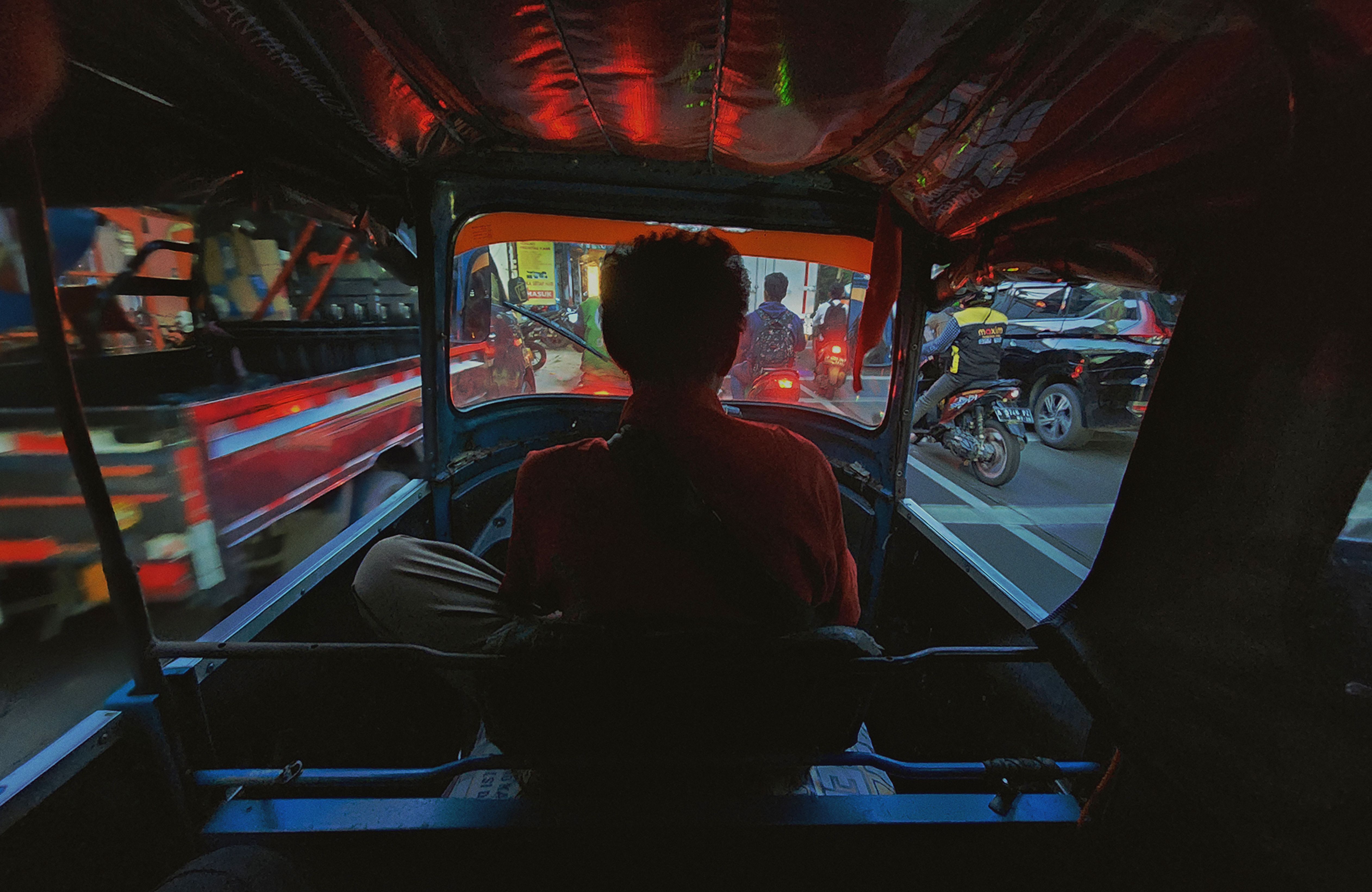 A tuk-tuk driving through a bustling street in Phnom Penh, Cambodia, with local architecture in the background