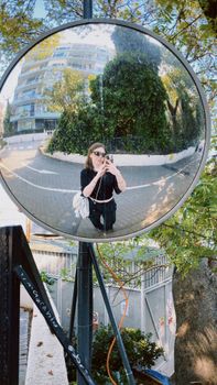 A person takes a photo through a reflective street mirror in Istanbul.