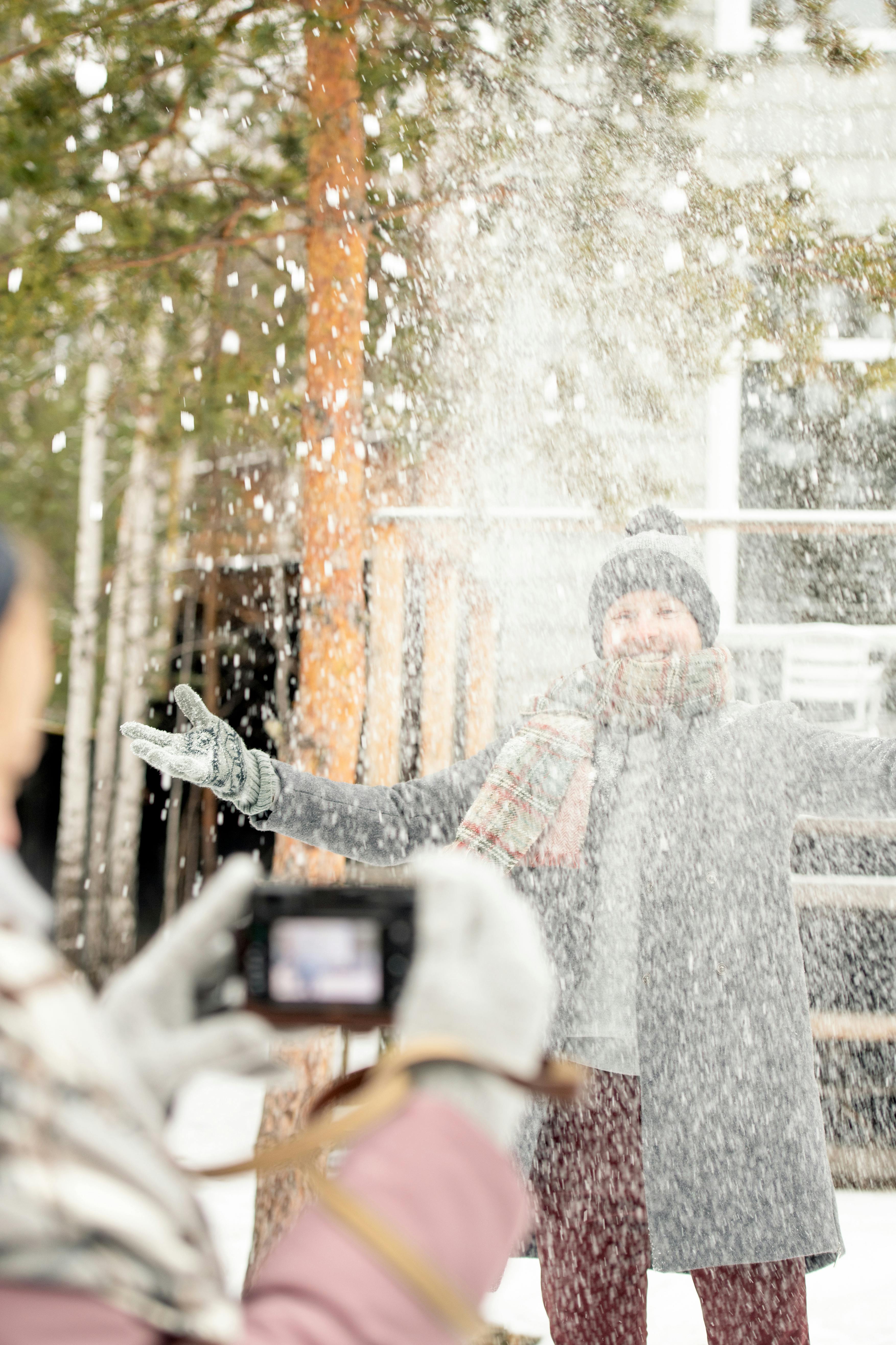 一名男子在白雪皑皑的冬日里，于户外拍照，享受着周围飘落的雪