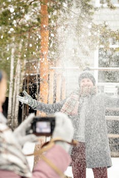 一名男子在白雪皑皑的冬日里，于户外拍照，享受着周围飘落的雪