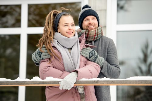Free A joyful couple bundled up in winter clothing, enjoying a snowy day together. Stock Photo