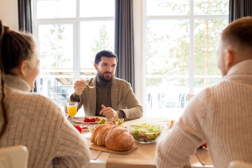 Free Adults having a warm indoor breakfast together with pastries and juice. Stock Photo
