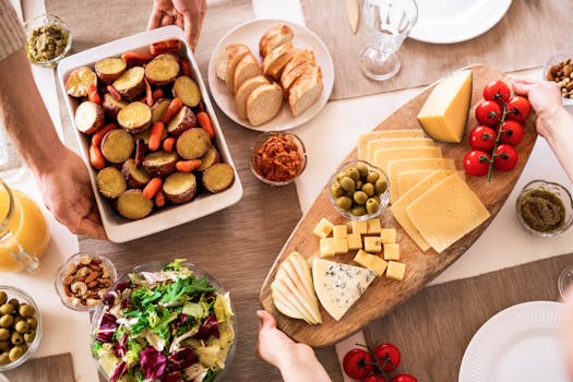 Delicious cheese platter with fresh vegetables, olives, and bread on a dining table.