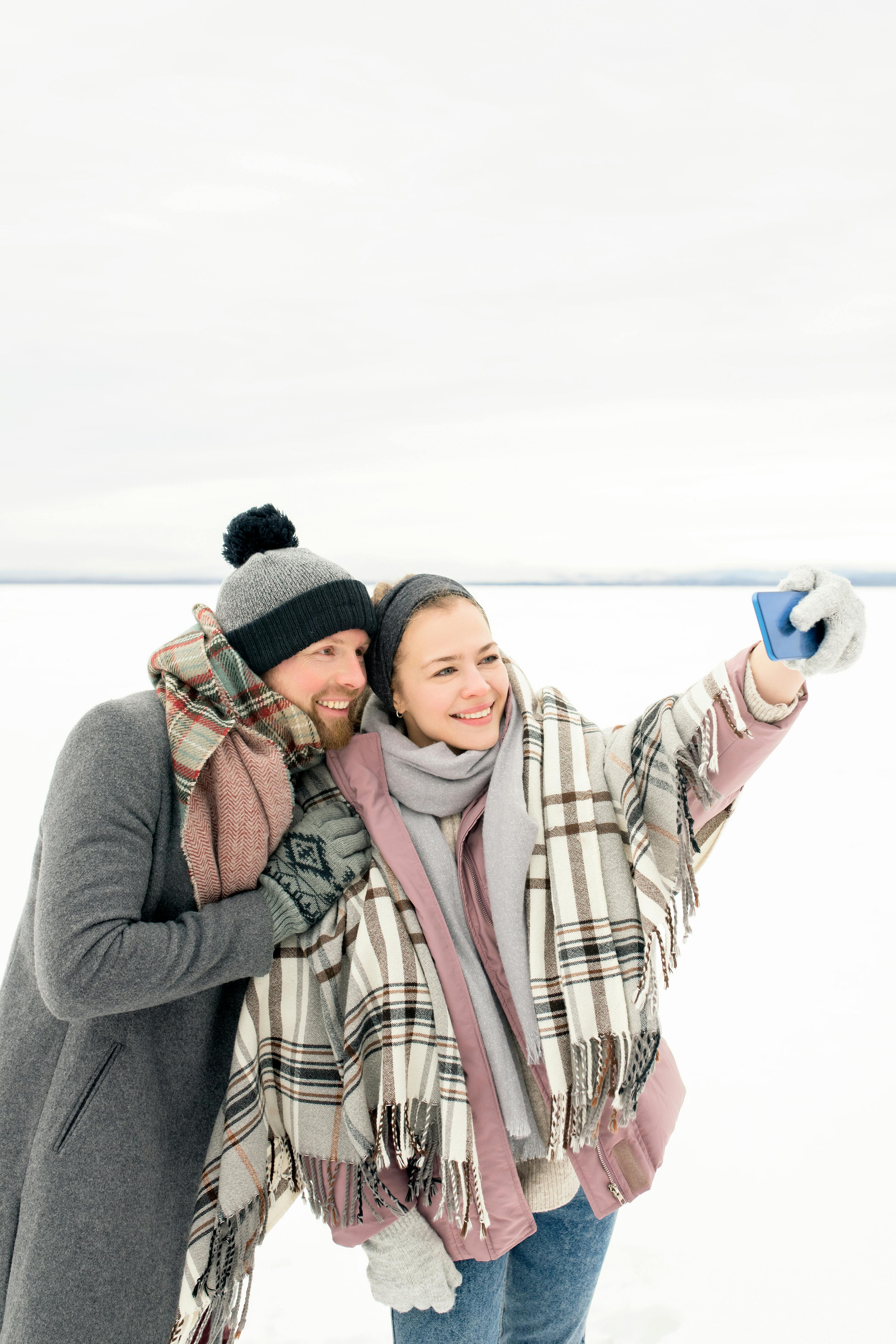 一对情侣在白雪皑皑的户外微笑着，捕捉快乐的冬日时刻