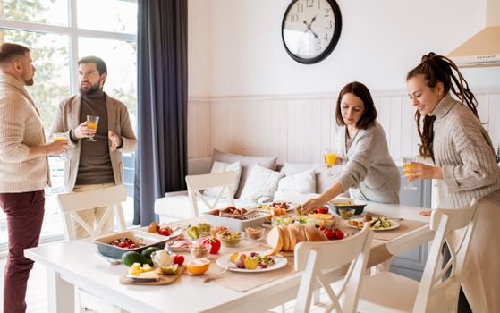 Cozy indoor gathering with friends enjoying a meal and orange juice on a bright day.