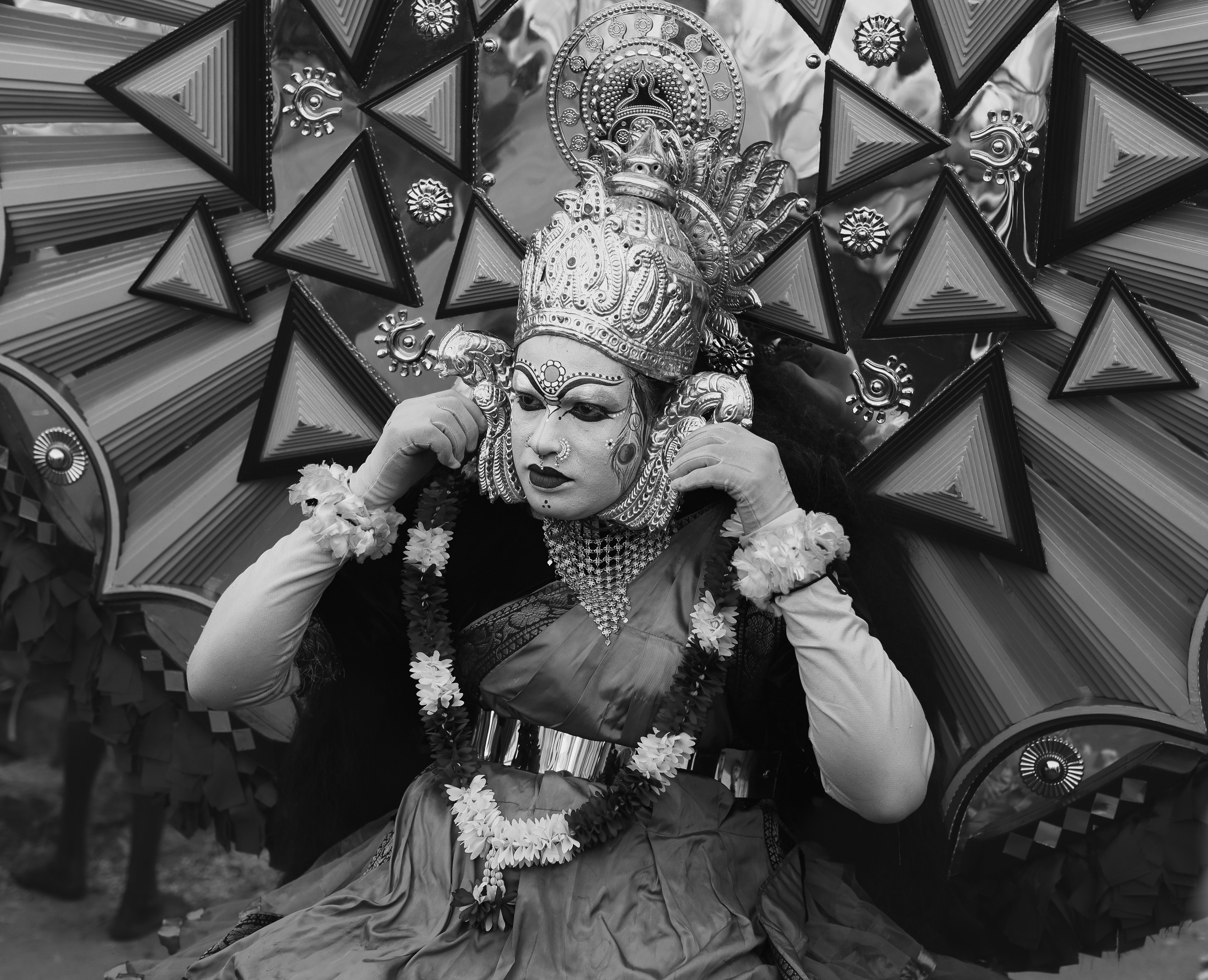 Black and white photo of a Kathakali performer in traditional costume and makeup during a cultural festival in Thrissur, India.