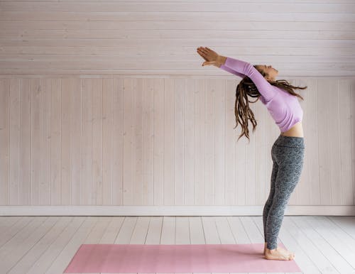 Vrouw In Roze Lange Mouwen Top En Grijze Beenkappen Die Yoga Doen