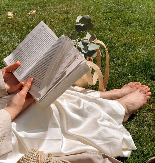 Free A person reading on grass with a floral bag in Killarney National Park, Ireland. Stock Photo