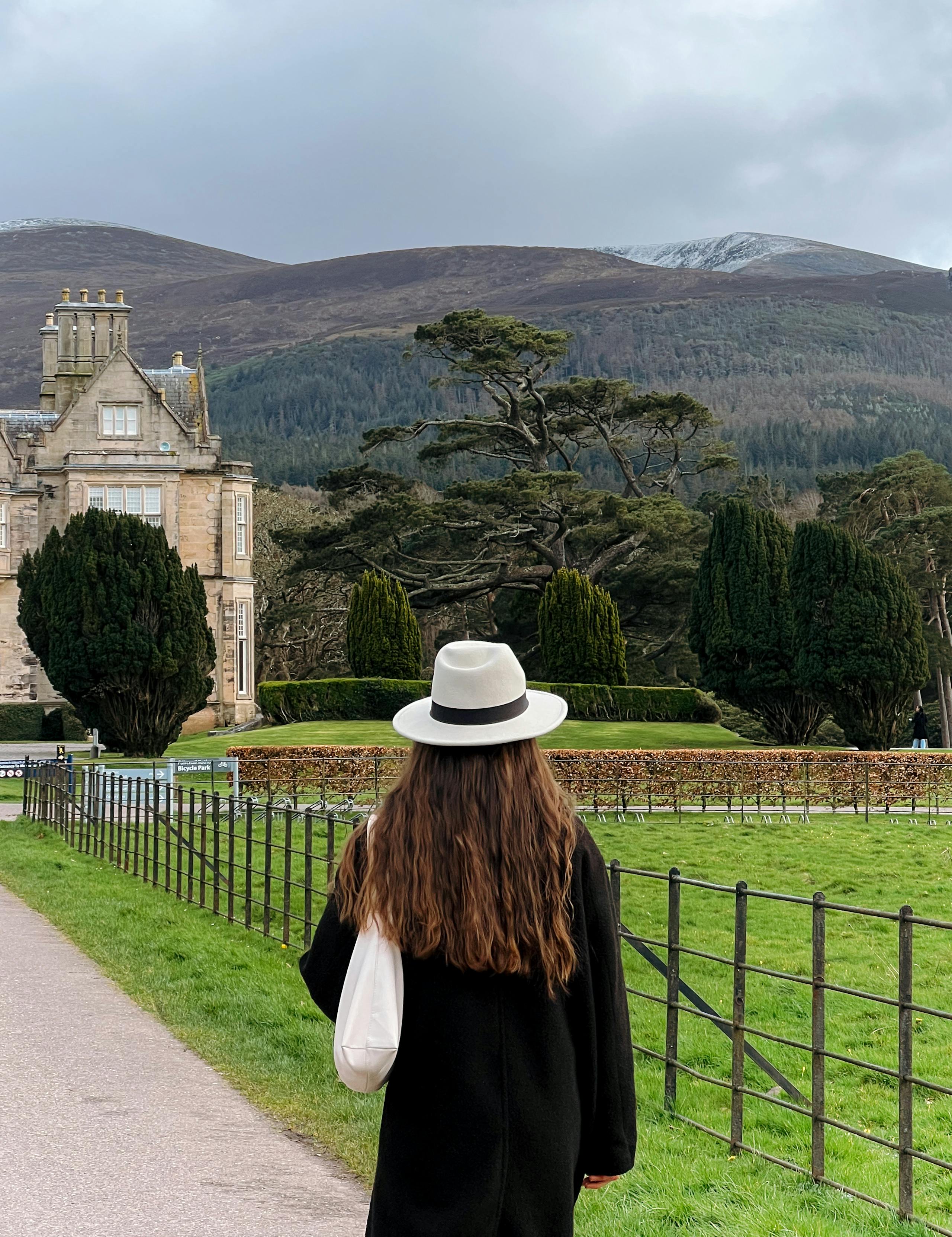 A woman with long hair and a hat enjoys the view at Killarney National Park in Ireland.