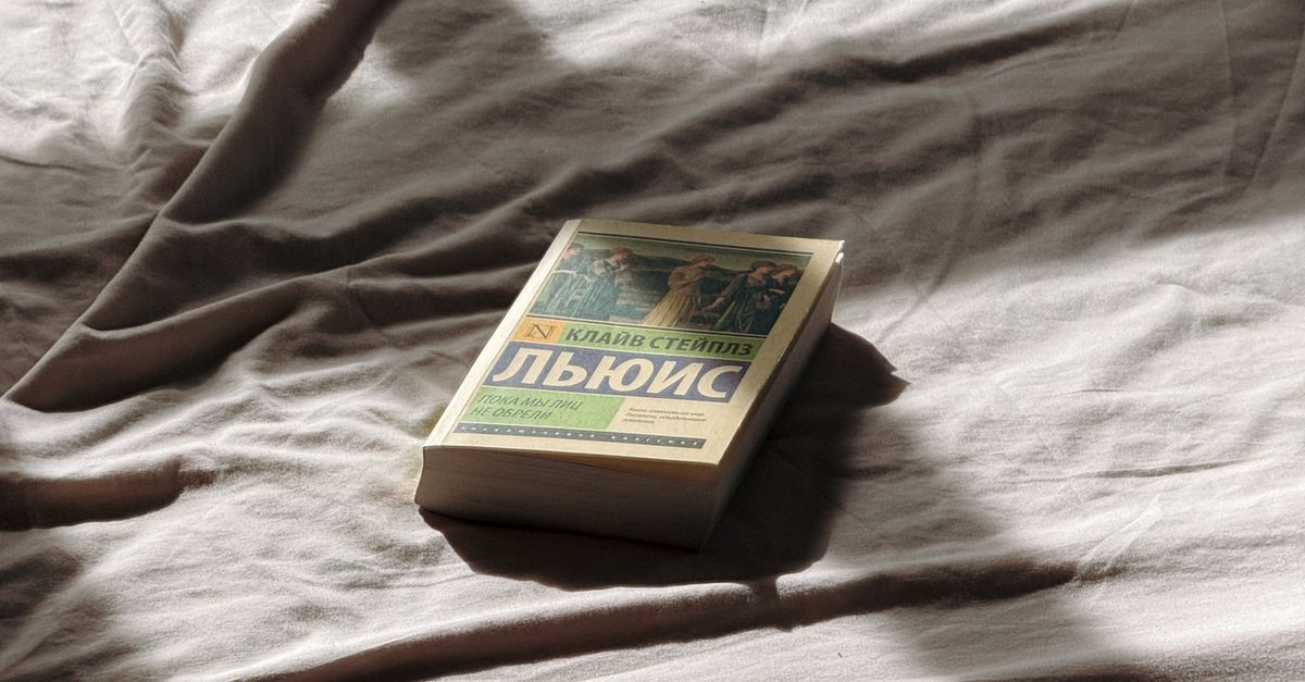 woman reading book in bed with sunlight