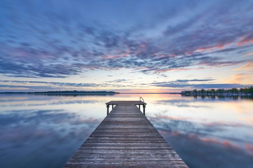 Free Peaceful sunrise view from a wooden pier over Chiemsee lake in Bavaria, Germany. Stock Photo