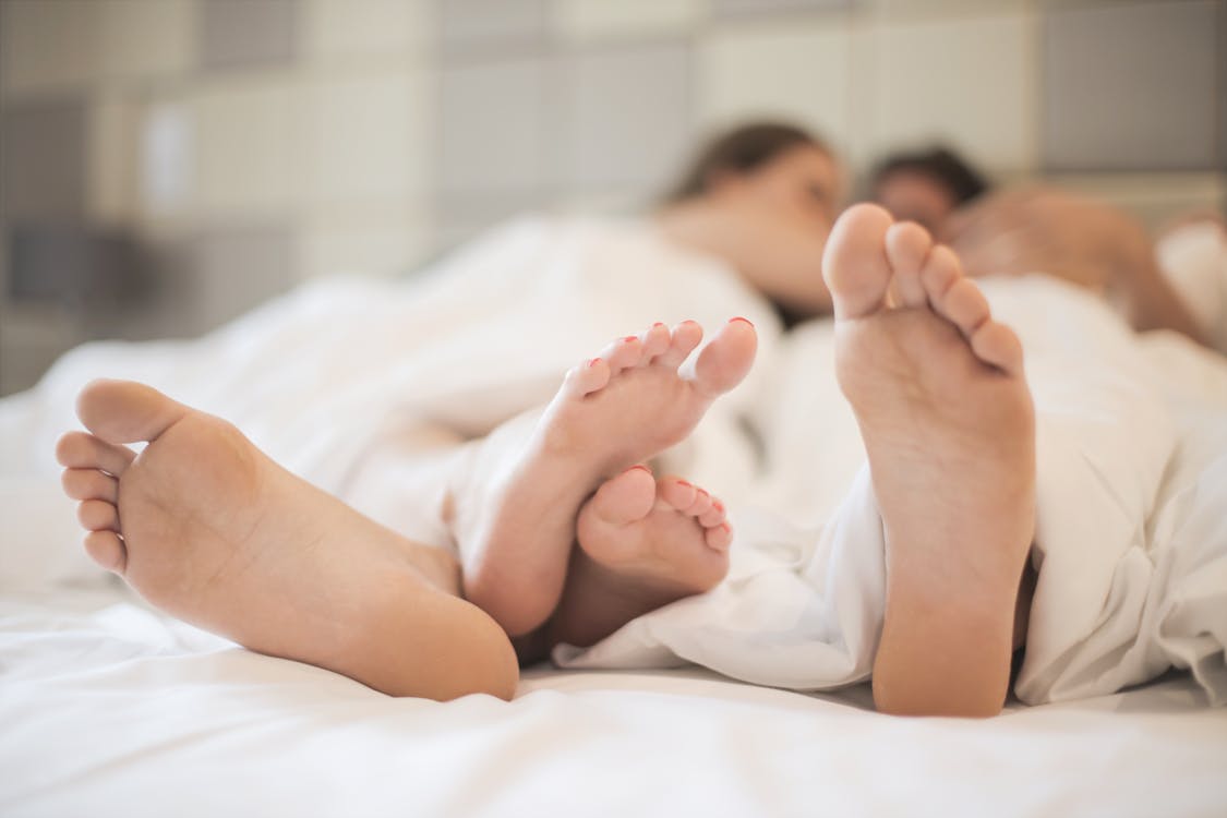 Free Feet of couple in love in bed Stock Photo