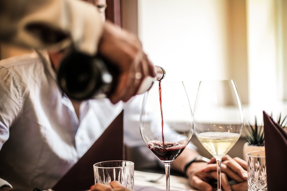 Free Crop man pouring red wine in glass in restaurant Stock Photo