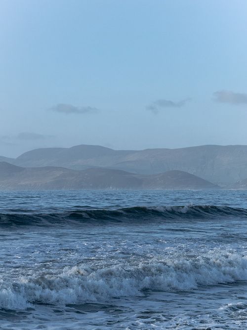 Free Peaceful waves and distant hills under a twilight sky along the Irish coast, capturing tranquility. Stock Photo