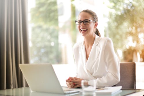 Free 在办公室用笔记本电脑工作的笑女商人 Stock Photo