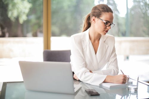 Empresaria Pensativa Tomando Notas En El Portátil En La Oficina Brillante