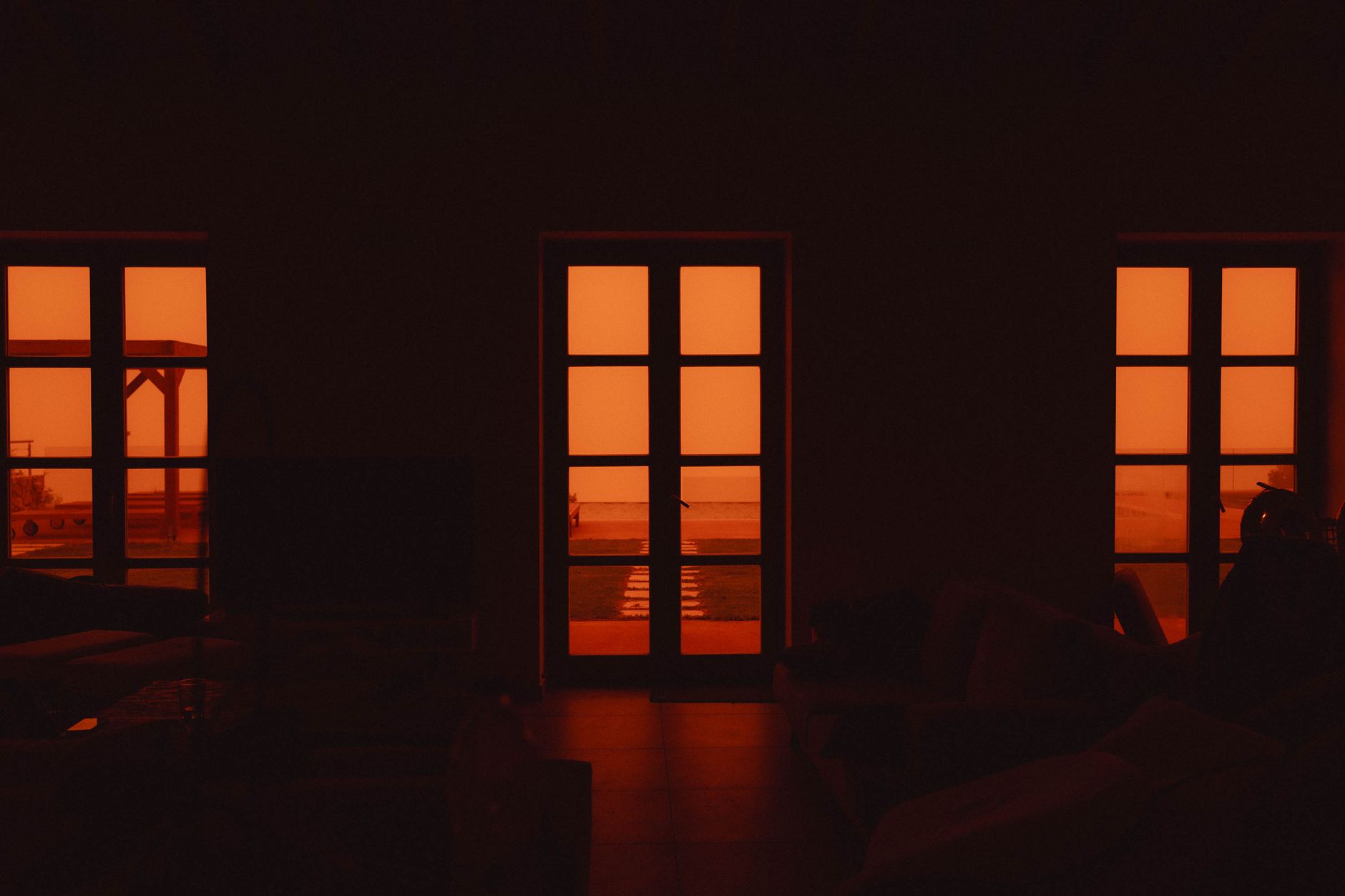 Indoor silhouette with a vivid orange glow from the windows, suggesting warmth and sunset ambiance.