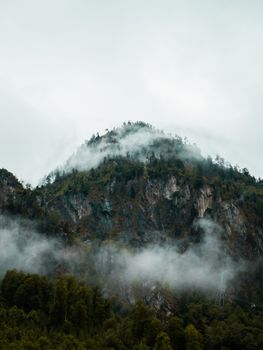 拍摄奥地利一座雾气缭绕的山峰，展现薄雾中大自然的宁静